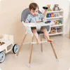 A baby sitting in a high chair playing with toys, with shelves of toys in the background. Náhled obrázku produktu
