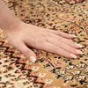 A hand is shown resting on a rug with an oriental pattern. Produktbild-Vorschau