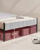 Underneath a bed frame, showing storage boxes and a robotic vacuum cleaner. Náhled obrázku produktu