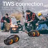 Two men are sitting around a campfire with two portable speakers in the foreground. Podgląd zdjęcia produktu