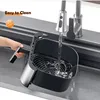 A hand is holding an air fryer basket under a running faucet in a sink. Podgląd zdjęcia produktu