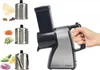 A hand holding an electric vegetable slicer with various attachments and chopped vegetables displayed around it. Produktbild-Vorschau