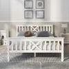 A white wooden bed frame with a slatted headboard and footboard, set up in a bedroom with decorative pillows and a rug. Produktbild-Vorschau