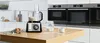 A modern kitchen counter with a food processor, eggs, and jars. Voir les images du produit