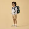 A young boy wearing a backpack stands against a plain background. Podgląd zdjęcia produktu