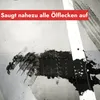 A close-up of an oil spill on a concrete surface, with a red banner overlaying the top. Produktbild-Vorschau