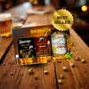 A gift set of three mustard jars, presented on a wooden table with scattered spices and a glass of beer in the background. Produktbild-Vorschau