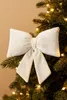 A cream-colored velvet bow is attached to a decorated Christmas tree branch. Podgląd zdjęcia produktu
