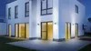 A modern white house with outdoor lighting at dusk. Produktbild-Vorschau