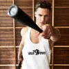 A man in a white tank top with a logo is holding a black baseball bat, looking intensely at the camera. The background is made of wooden planks. Produktbild-Vorschau