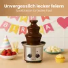 A chocolate fountain is set up on a wooden table, surrounded by party decorations and treats like strawberries, marshmallows, and a cupcake. The scene suggests a festive celebration. Podgląd zdjęcia produktu