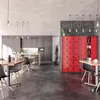 A modern break room or office common area with kitchen cabinets, tables, chairs, and red lockers. Anteprima dell’immagine prodotto