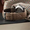 A close-up view of a watch strap and case back, with a patterned fabric in the background. Voir les images du produit