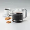 A coffee pot filled with coffee, a cup of coffee, and cookies on a white surface. Podgląd zdjęcia produktu