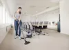 A woman is vacuuming a conference room with a commercial vacuum cleaner. Produktbild-Vorschau