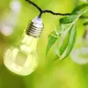 A string of solar-powered LED light bulbs resembling traditional incandescent bulbs, hanging from a black wire and intertwined with green leaves and branches. Anteprima dell’immagine prodotto