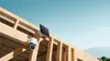 A security camera with a solar panel attached to the wooden frame of a building under construction. Náhľad obrázku produktu