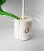 A green watering can pouring water into a white base for a patio umbrella stand. Produktbild-Vorschau