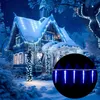 A snow-covered house decorated with blue LED icicle lights at night. Produktbild-Vorschau