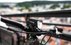 A bicycle handlebar with a front light attached, with a blurred cityscape in the background. Anteprima dell’immagine prodotto