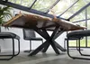 A dining table with a live edge wood top and a black metal cross base, set in a room with large windows and chairs. Voir les images du produit
