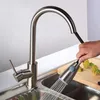 A person is using a pull-down kitchen faucet to rinse vegetables on a cutting board in a kitchen sink. Náhľad obrázku produktu