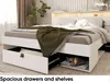 A modern white bed with integrated storage drawers and shelves, featuring a cat sleeping in one of the open shelves. A green throw blanket is draped over the bed. Produktbild-Vorschau