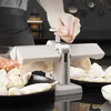 A person is using a dumpling maker to create dumplings, with finished dumplings on plates in the foreground. Podgląd zdjęcia produktu