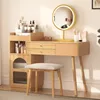 A vanity table with a mirror, drawers, and a side cabinet, along with a stool, set up in a room. Náhled obrázku produktu