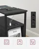 A black wooden side table with two drawers is shown, with a power strip integrated into the top. Tablets and smartphones are charging on the table. Icons representing power outlets, USB ports, and cables are displayed below. Náhled obrázku produktu