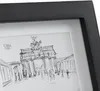 A close-up view of a framed sketch of the Brandenburg Gate, with people depicted in the foreground. Produktbild-Vorschau