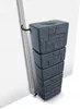 A dark gray, stacked rain barrel with a stone-like texture, positioned next to a downspout against a white, textured wall. Anteprima dell’immagine prodotto