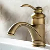 A close-up shot of a retro-style brass faucet on a white sink, with a marble-patterned wall in the background. Produktbild-Vorschau