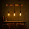 A pendant light fixture with three Edison bulbs hangs above a wooden table with leather chairs. Produktbild-Vorschau