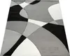 A close-up, angled view of a modern geometric rug with a black, white, and gray abstract pattern. Produktbild-Vorschau