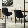 Two black velvet dining chairs are shown in a dining room setting. Náhľad obrázku produktu