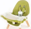 A close-up view of a green high chair with a baby bottle on the tray. Produktbild-Vorschau