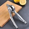 A manual citrus juicer is placed on a wooden cutting board next to lemons. Produktbild-Vorschau