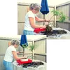A woman is repotting a plant on a table outdoors. Produktbild-Vorschau