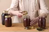 A person is shown assembling jars of preserves. Voir les images du produit