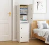 A white modular shelving unit filled with folded clothes, towels, and a package of tissues, placed next to a door and a bed in a bedroom. Anteprima dell’immagine prodotto