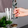 A hand holding a clear glass mug in a kitchen setting. Voir les images du produit
