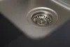 A close-up view of a stainless steel sink drain with a strainer. Produktbild-Vorschau