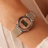 A close-up shot of a woman's wrist wearing a silver Casio digital watch with a pink face. Produktbild-Vorschau