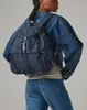 A person wearing a denim jacket and jeans, carrying a blue backpack. Voir les images du produit