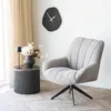 A modern living room scene featuring a chair, side table with a lamp and vase of flowers, and a wall clock. Voir les images du produit
