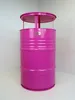 A bright pink barrel-shaped table with a silver logo on the front, set in a corner against a white and light gray background. Produktbild-Vorschau