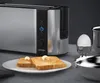 A toaster with two slices of toast, an egg in an egg cup, and a bowl. Produktbild-Vorschau