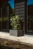 A rectangular planter with a plant in it, placed on gravel next to a modern house. Náhľad obrázku produktu