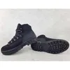 A pair of black hiking boots on a light gray textured surface. Podgląd zdjęcia produktu